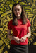 Person wearing a red shirt standing in front of a textured yellow wall